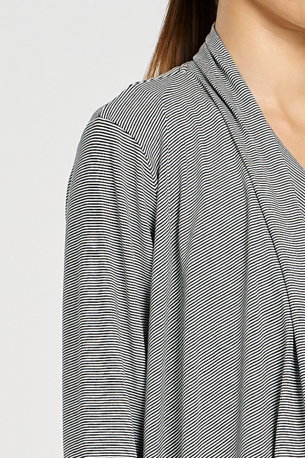 Close-up of a person wearing a black and white striped shirt against a light gray background