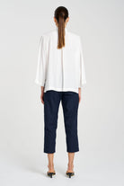 Person wearing a white blouse and navy pants on a white background