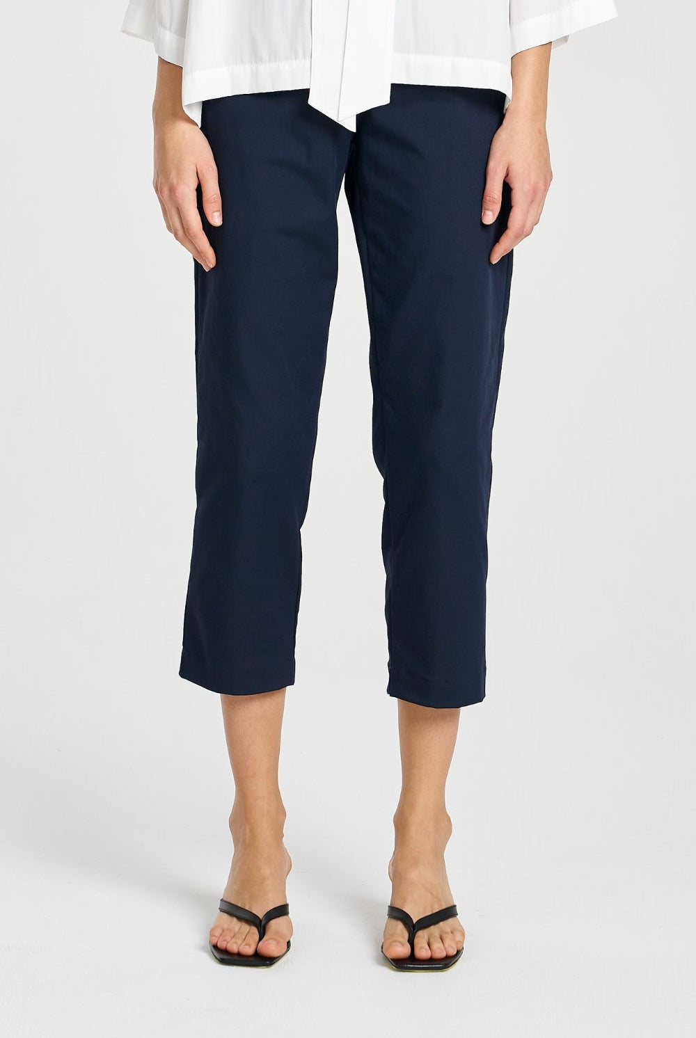 Person wearing navy blue pants and a white shirt on a white background
