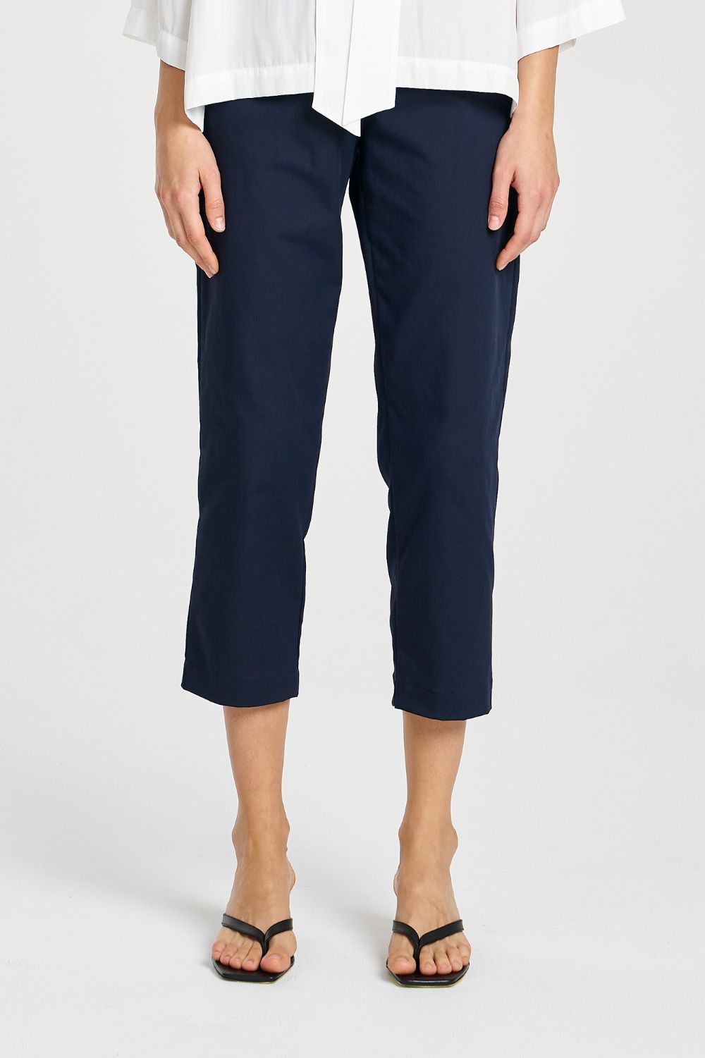 Person wearing navy blue pants and a white shirt on a white background