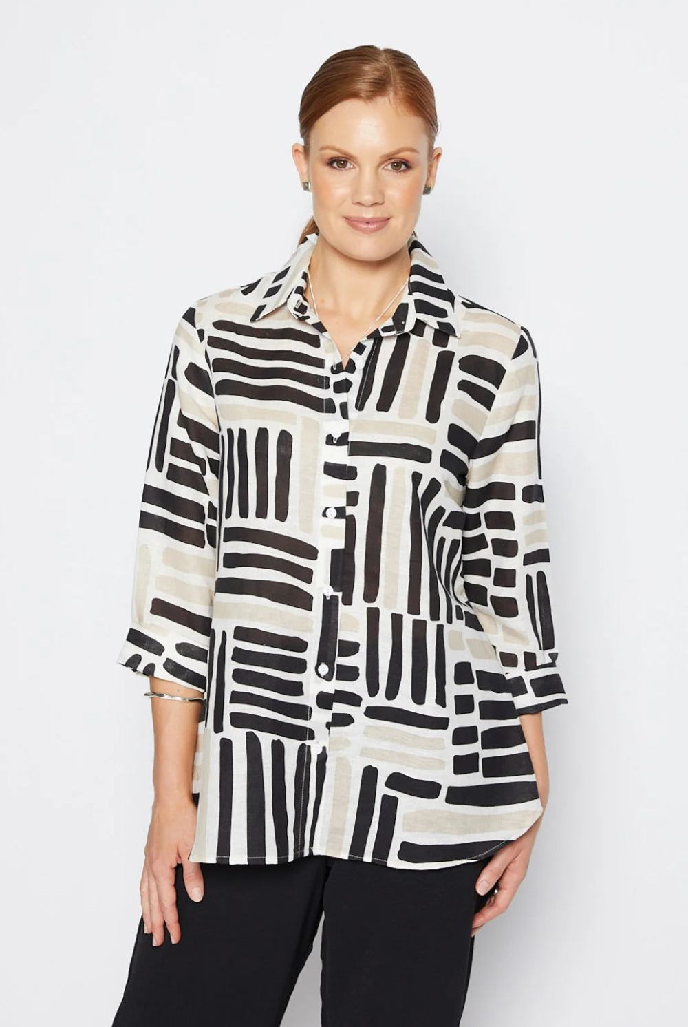 Woman wearing a black and white patterned shirt against a plain background