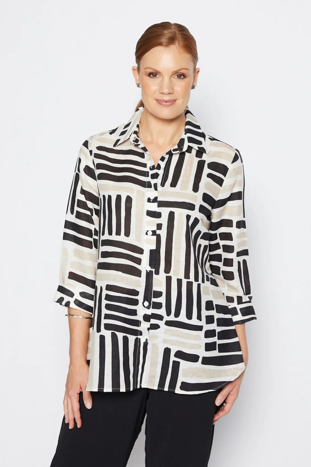 Woman wearing a black and white patterned shirt against a plain background
