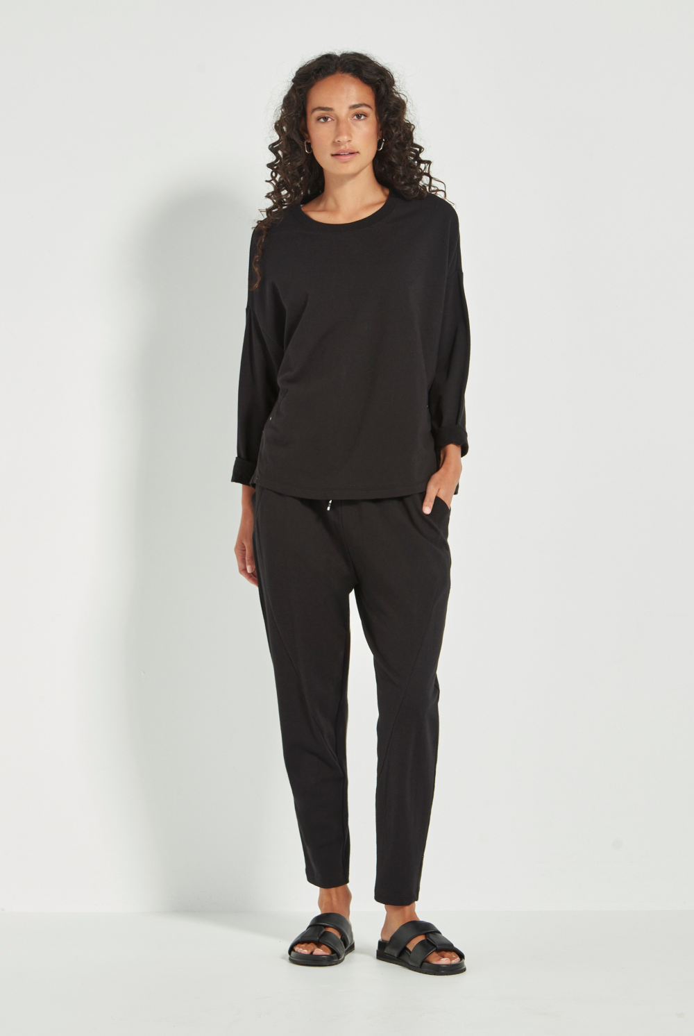 Woman wearing the Verge Downtown Sweater in Black with black pants, available online at Silvermaple Boutique.