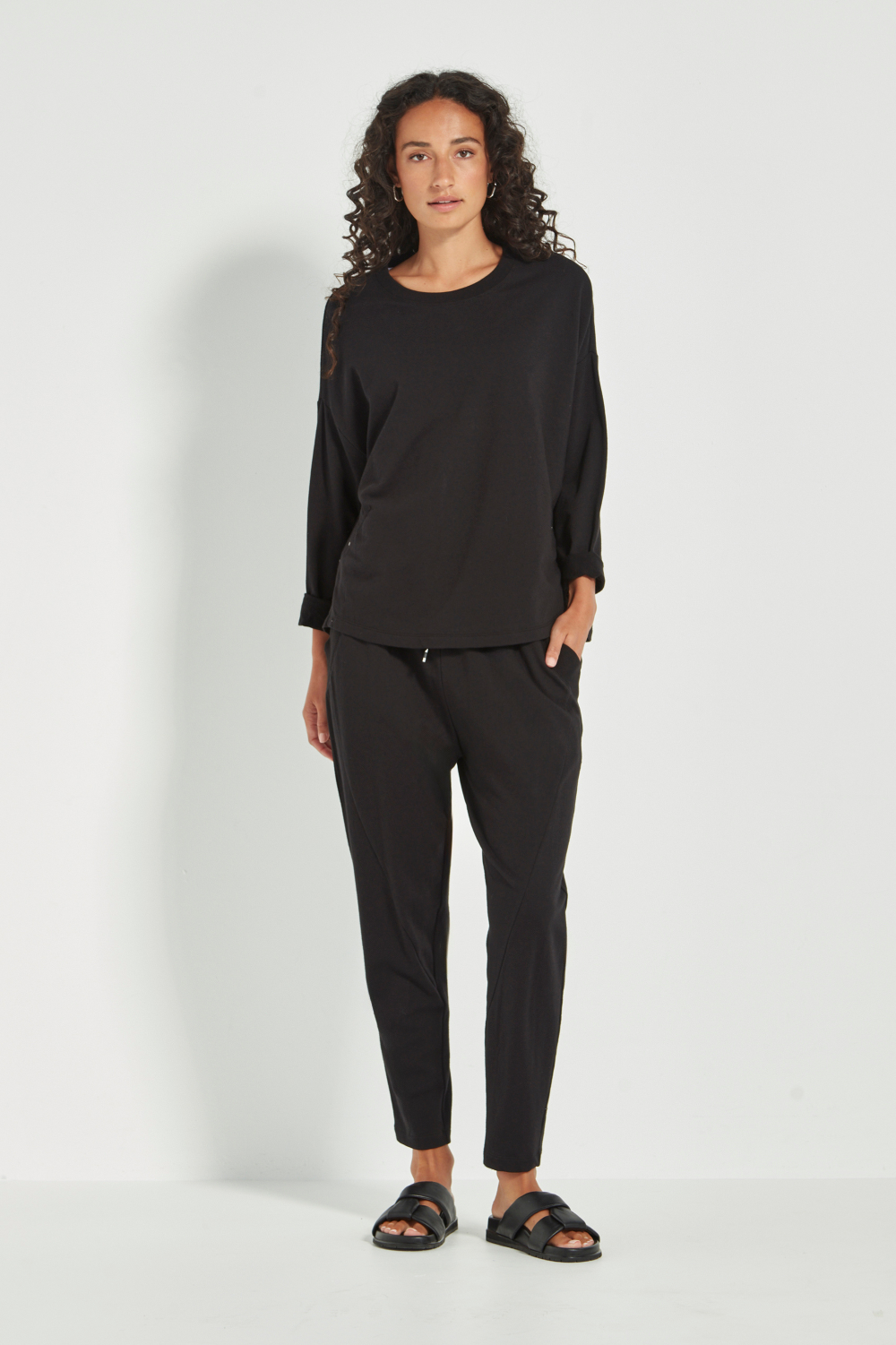 Woman wearing the Verge Downtown Sweater in Black with black pants, available online at Silvermaple Boutique.