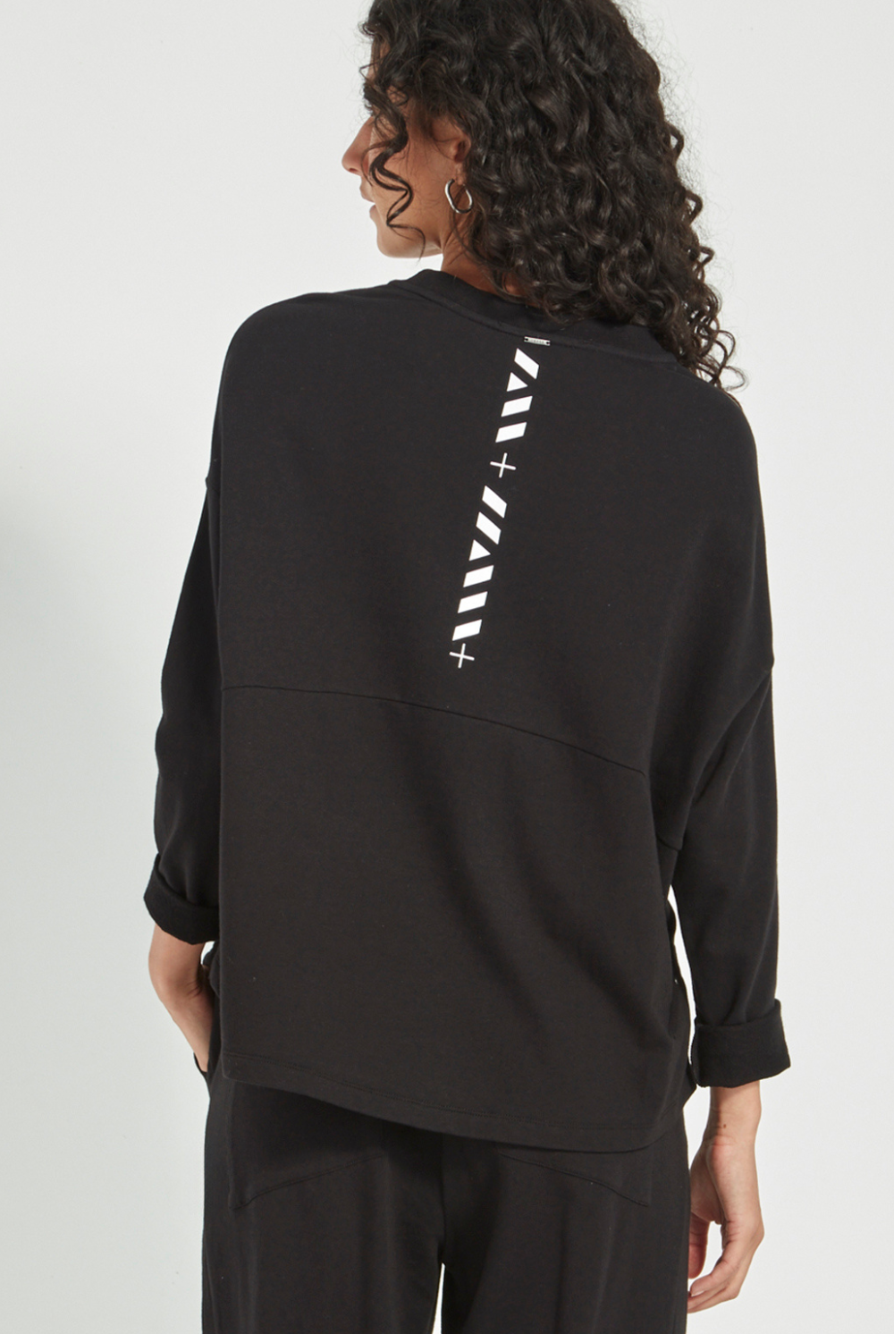 Woman wearing the Verge Downtown Sweater in Black with black pants, available online at Silvermaple Boutique.
