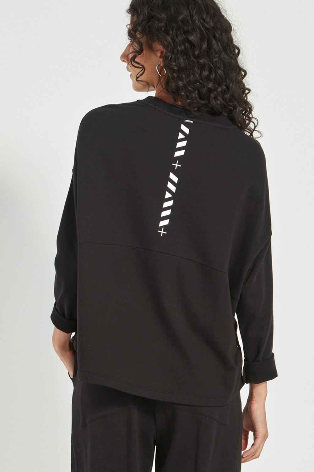 Woman wearing the Verge Downtown Sweater in Black with black pants, available online at Silvermaple Boutique.