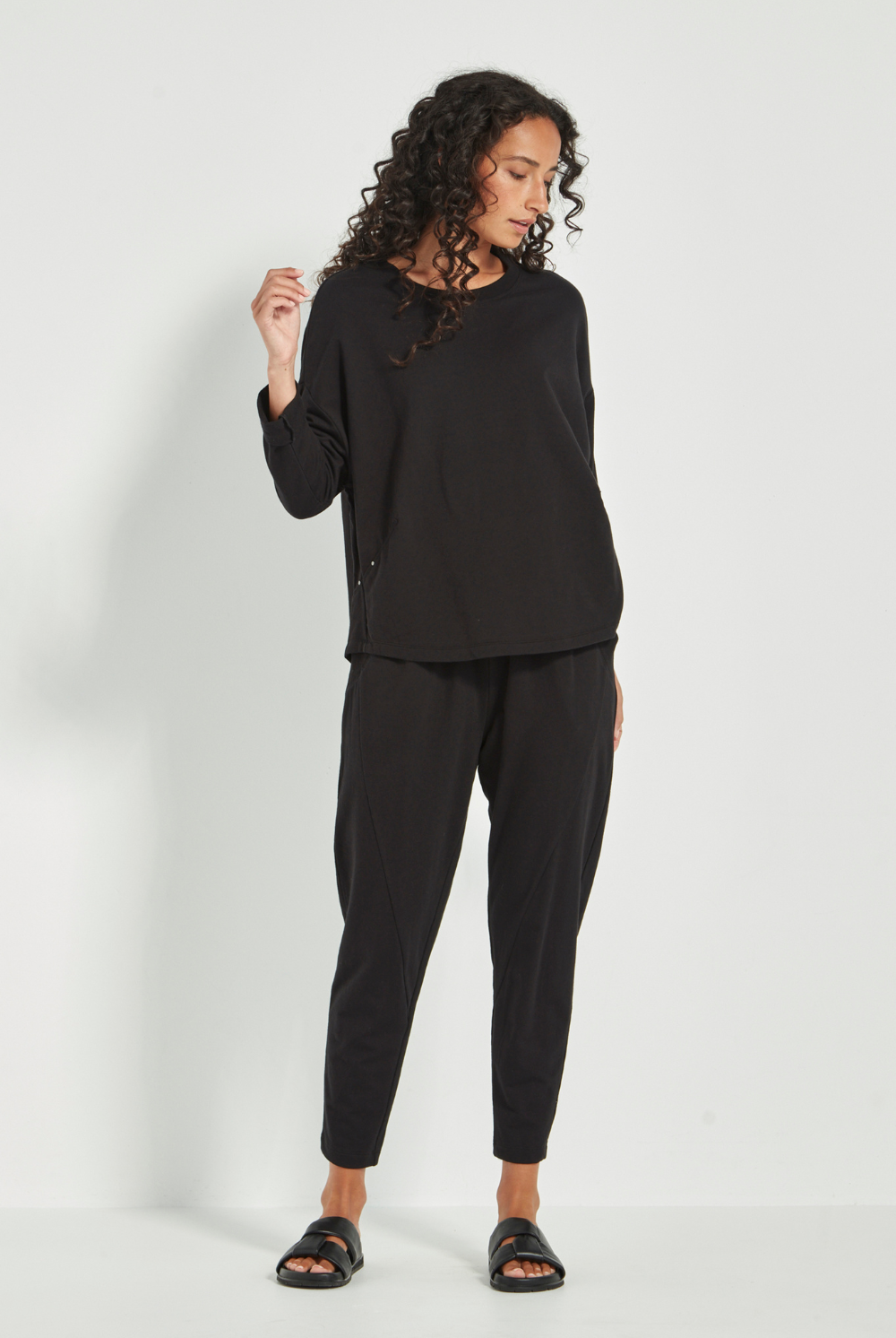 Woman wearing the Verge Downtown Sweater in Black with black pants, available online at Silvermaple Boutique.