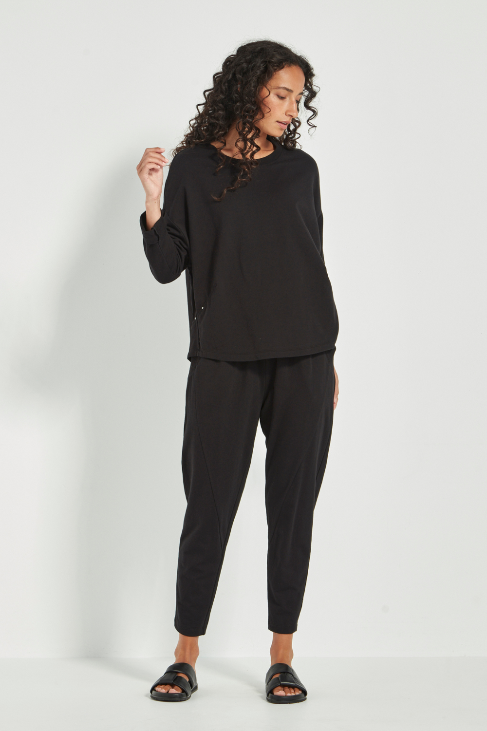 Woman wearing the Verge Downtown Sweater in Black with black pants, available online at Silvermaple Boutique.