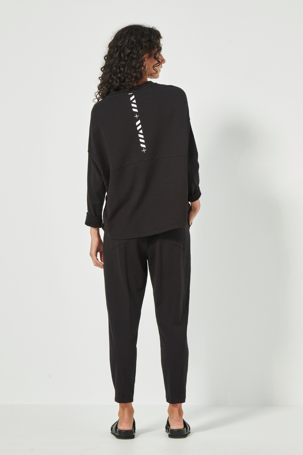 Woman wearing the Verge Downtown Sweater in Black with black pants, available online at Silvermaple Boutique.