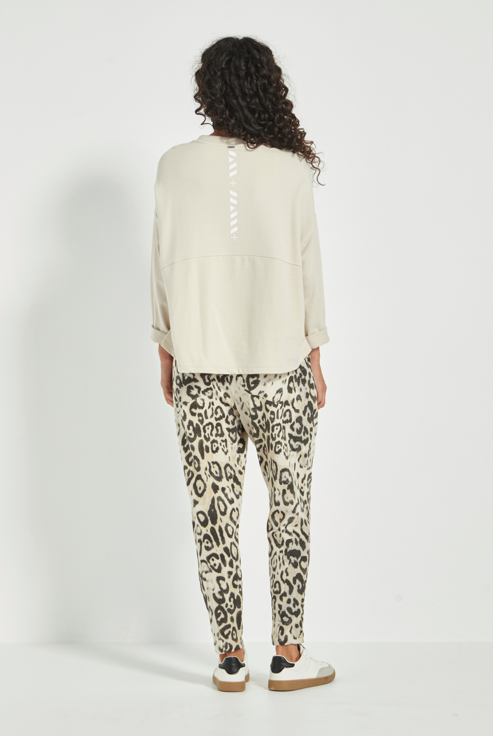 Woman wearing the new Verge Downtown sweater in cashew with leopard print pants, available online at Silvermaple Boutique.