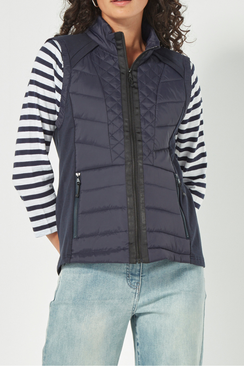 Woman wearing a striped shirt, Verge Idaho Vest Ink with light blue jeans on a white background. Available online at Silvermaple Boutique.