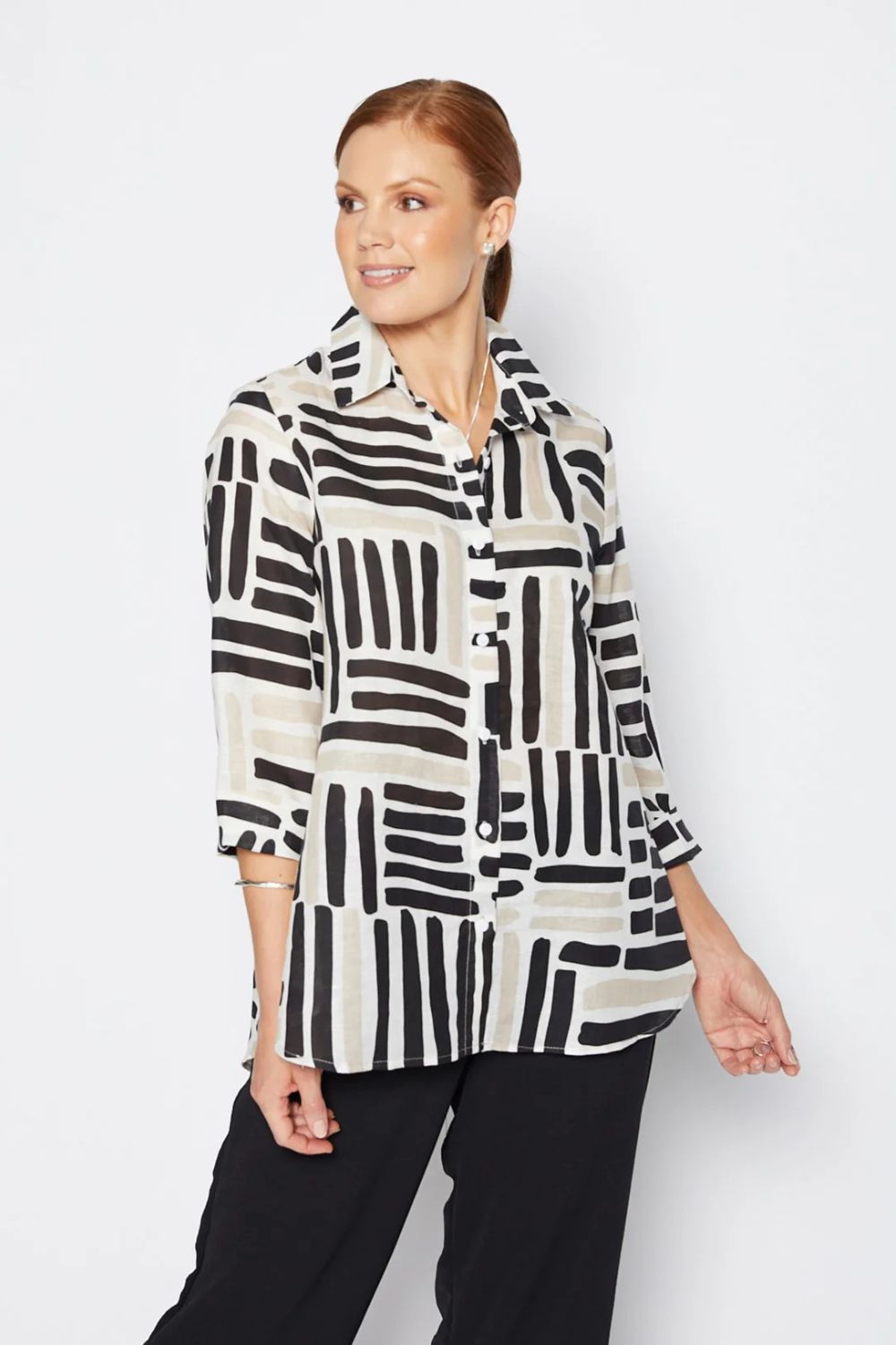 Woman wearing a patterned shirt with black and white geometric design on a plain background