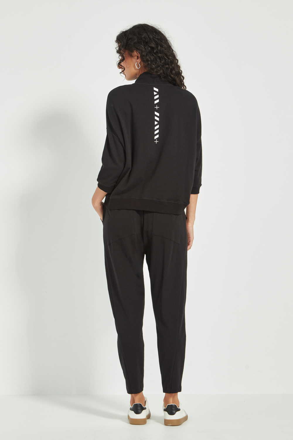 Woman wearing Verge Civic Pant, Black with a Black Top with white sneakers. Shop Silvermaple Boutique now