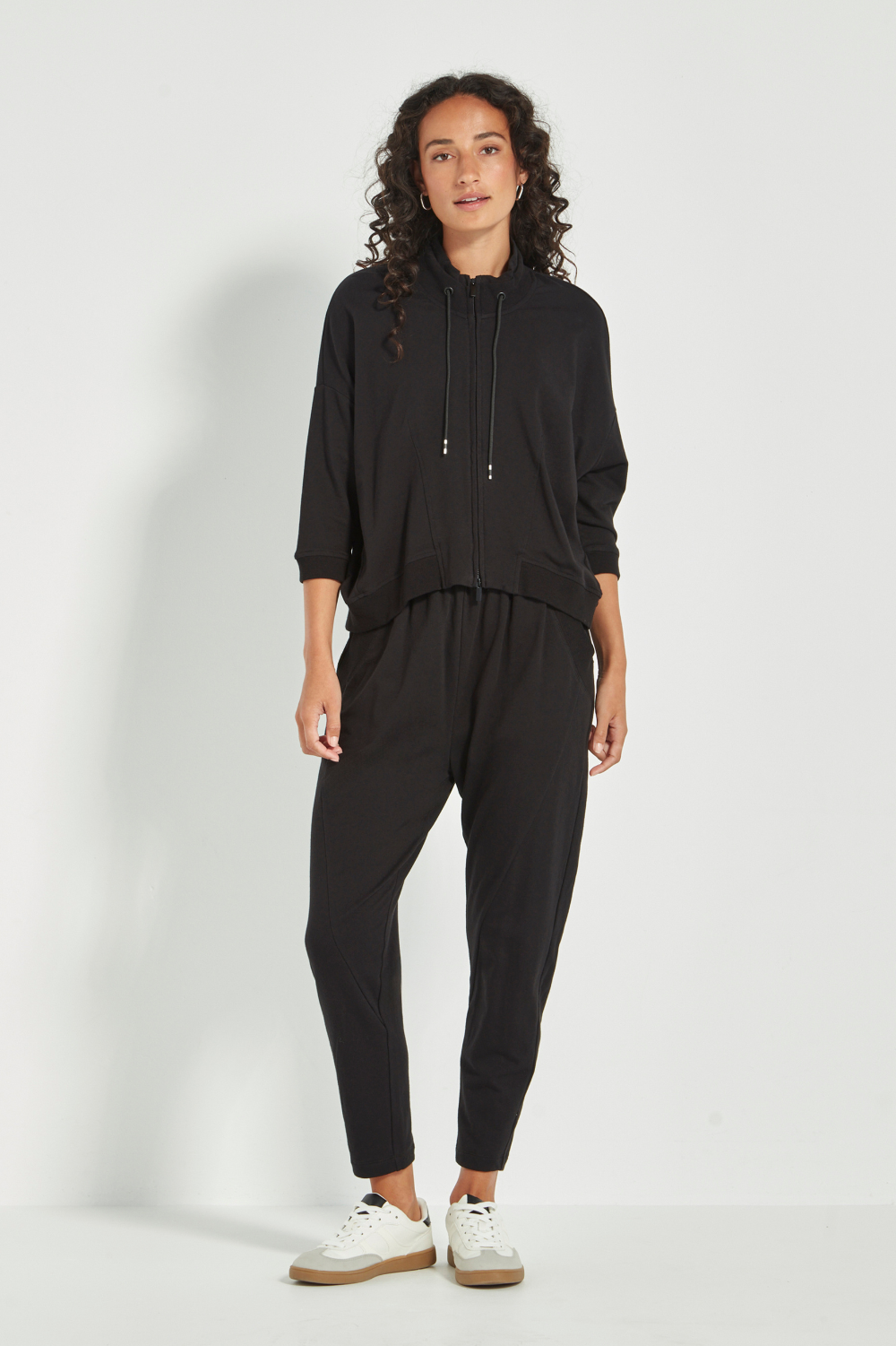 Woman wearing Verge Civic Pant, Black with a Black Top with white sneakers. Shop Silvermaple Boutique now.