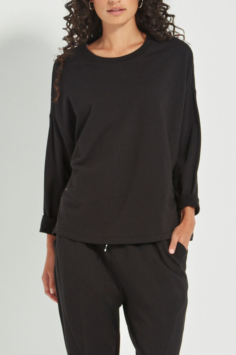Woman wearing the Verge Downtown Sweater in Black with black pants, available online at Silvermaple Boutique.