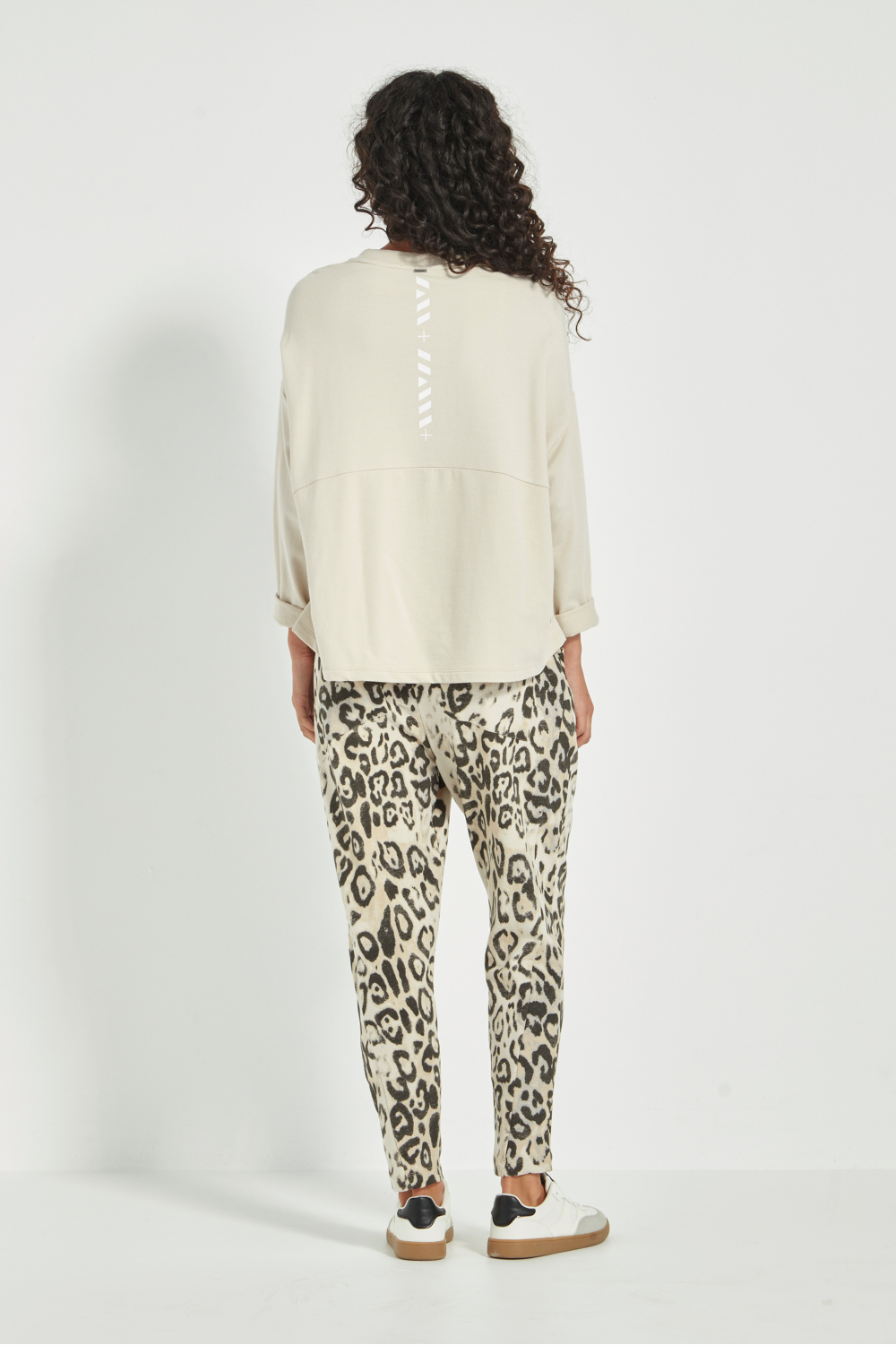 Woman wearing the new Verge Downtown sweater in cashew with leopard print pants, available online at Silvermaple Boutique. 