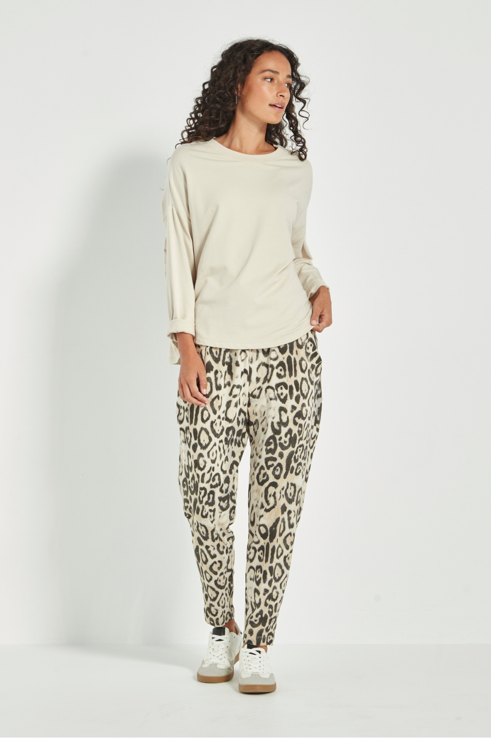 Woman wearing the new Verge Downtown sweater in cashew with leopard print pants, available online at Silvermaple Boutique. 